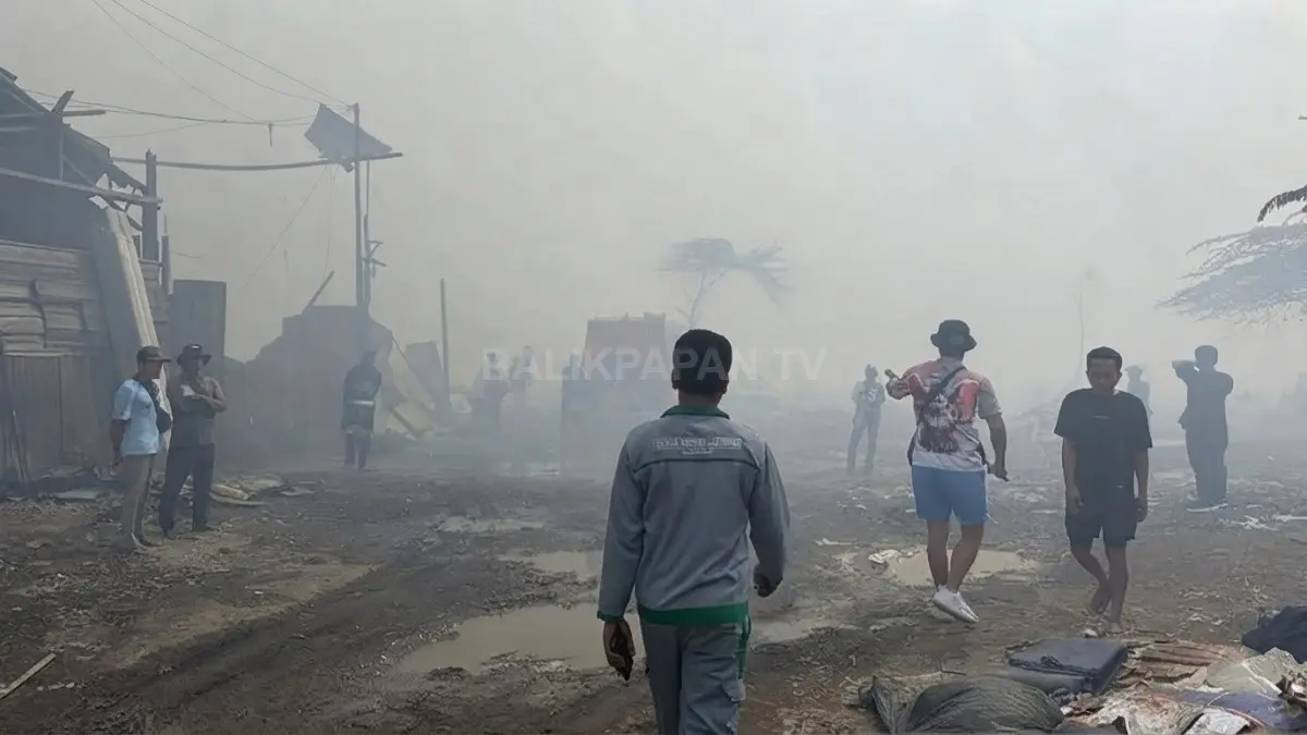 Asap tebal menyelimuti kawasan permukiman pascakebakaran, sementara warga menyusuri lokasi untuk memastikan kondisi dan keselamatan sekitar.