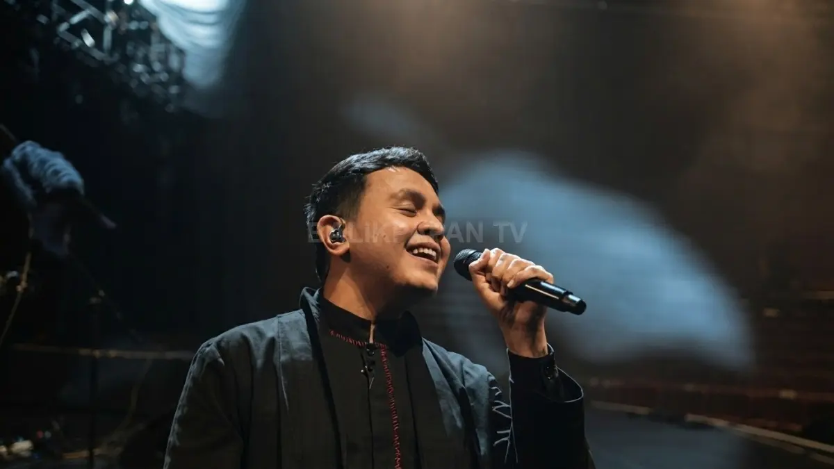 Aksi panggung Tulus yang bernyanyi penuh penghayatan di bawah tata cahaya panggung yang dramatis. (BTV/Ai)
