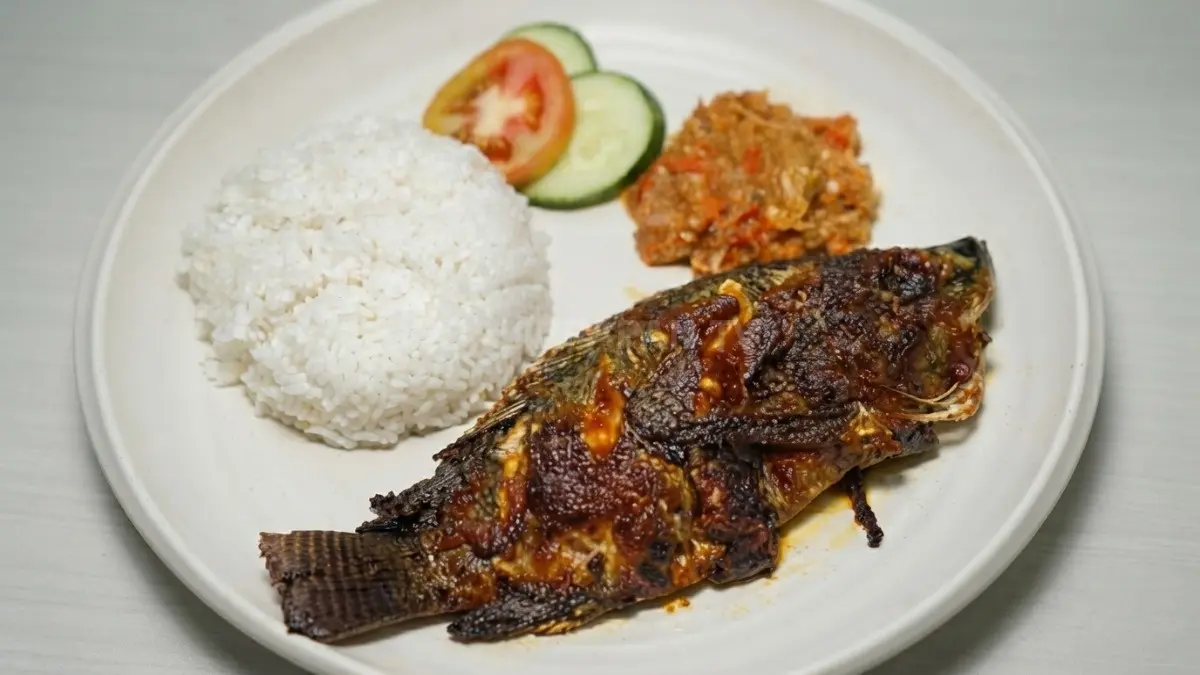 Ikan bandeng bakar kecokelatan disajikan bersama sambal tomat, lalapan, dan nasi putih hangat menggugah selera.
