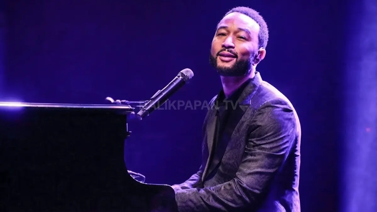 Penampilan emosional John Legend bernyanyi sambil memainkan piano di atas panggung dengan tata cahaya ungu. (BTV/Ai)