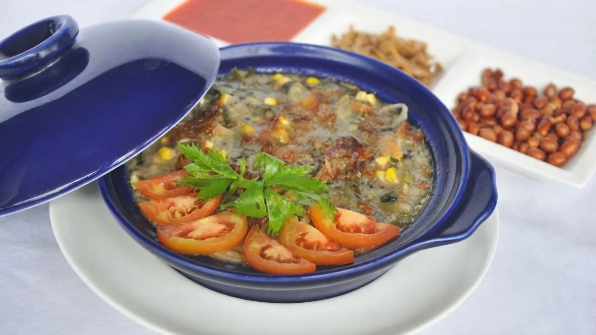 Bubur Pedas Sambas disajikan hangat dengan beragam sayuran, rempah, ikan teri dan kacang tanah sebagai pelengkap.