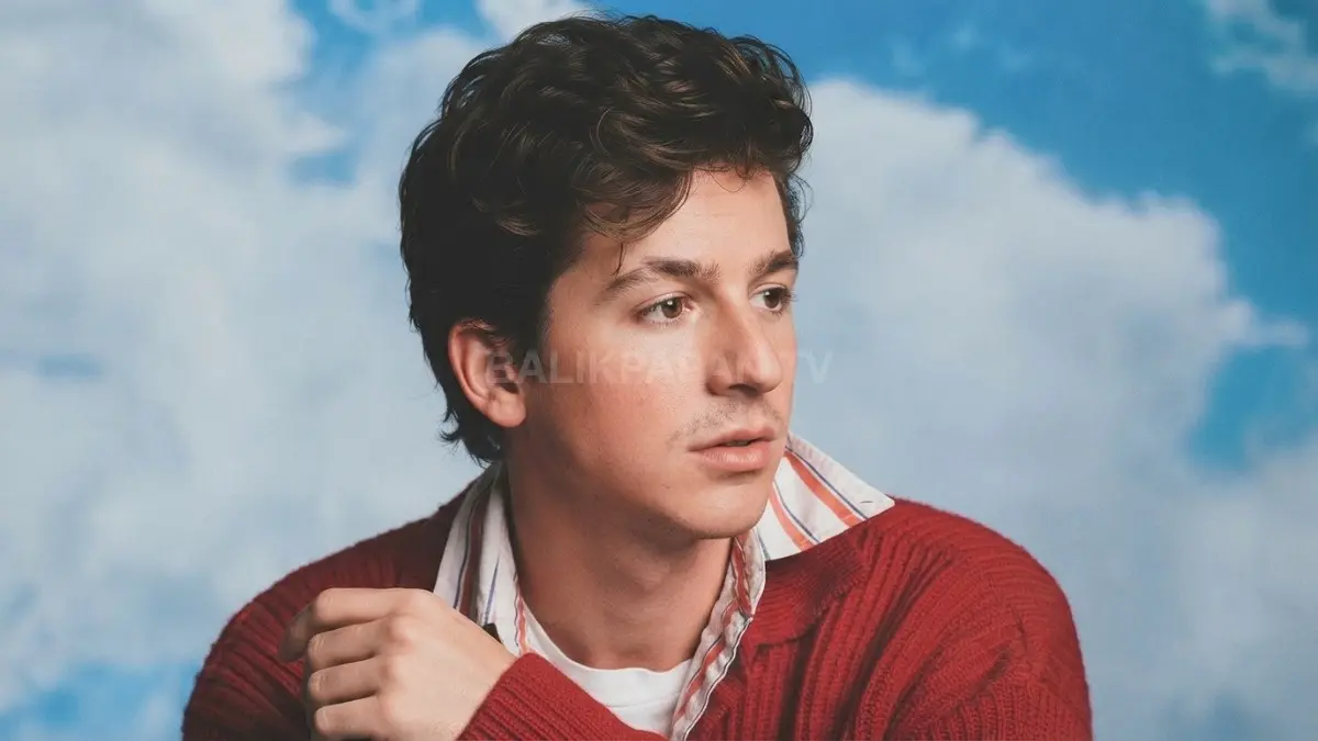 Potret santai Charlie Puth berbusana merah dengan latar belakang bernuansa awan kebiruan. (BTV/Ai)