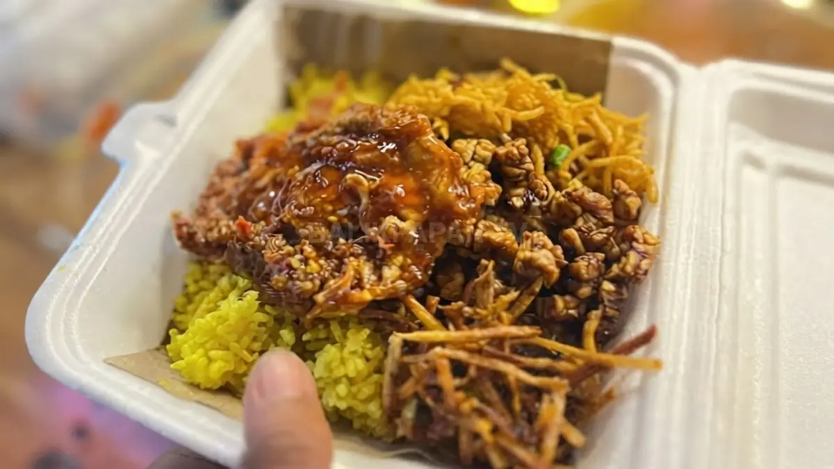 Nasi kuning Tarakan tersaji bersama lauk berbumbu, serundeng, sambal, dan bawang goreng dalam piring tradisional.
