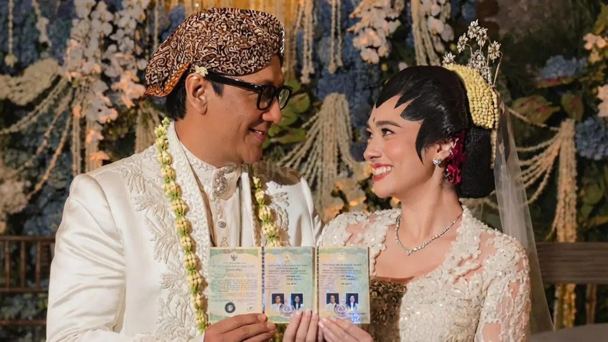 Andre Taulany dan Amanda Rigby berpose mengenakan pakaian adat Jawa sambil memamerkan buku nikah. (BTV/Ai)