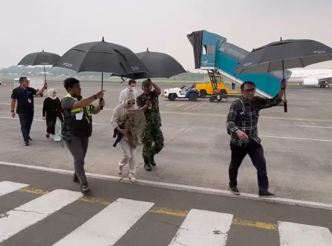 Syahrini dipayungi oleh anggota TNI saat turun dari jet pribadi.