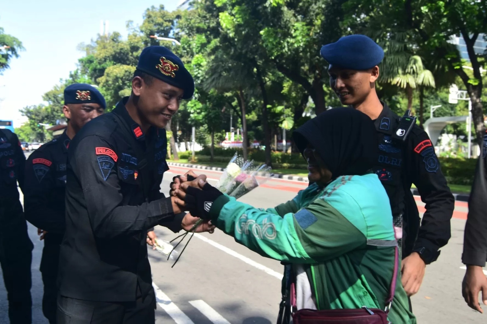 Driver ojol membagikan bunga mawar kepada aparat.