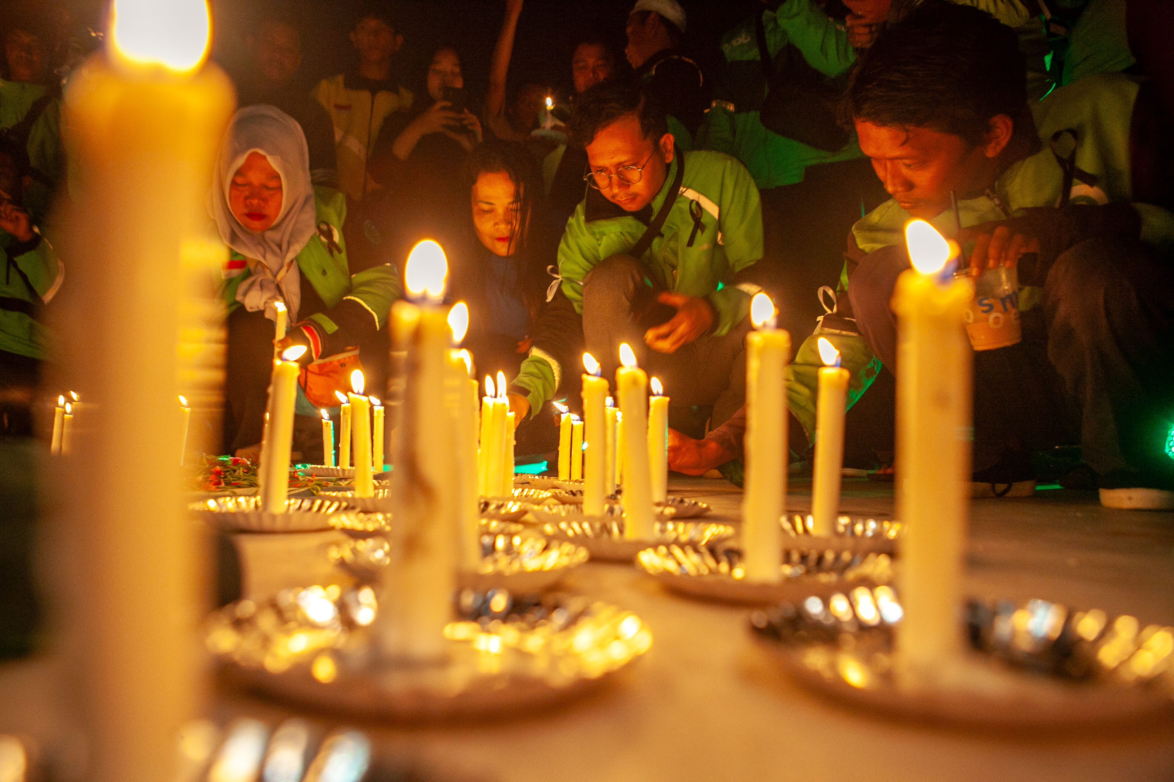 Para driver ojol saat menyalakan lilin, tabur bunga di Tugu Soekarno, Palangka Raya, Kamis malam (4/9/2025). PRATHAMA/KALTENG POS
