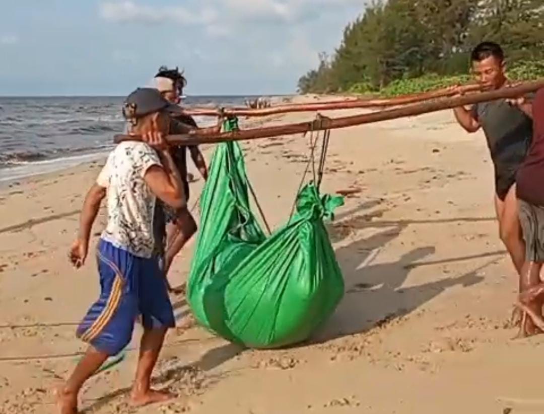 Nelayan membungkus dengan terpal jasad diduga korban kapal tenggelam.SCREENSHOOT