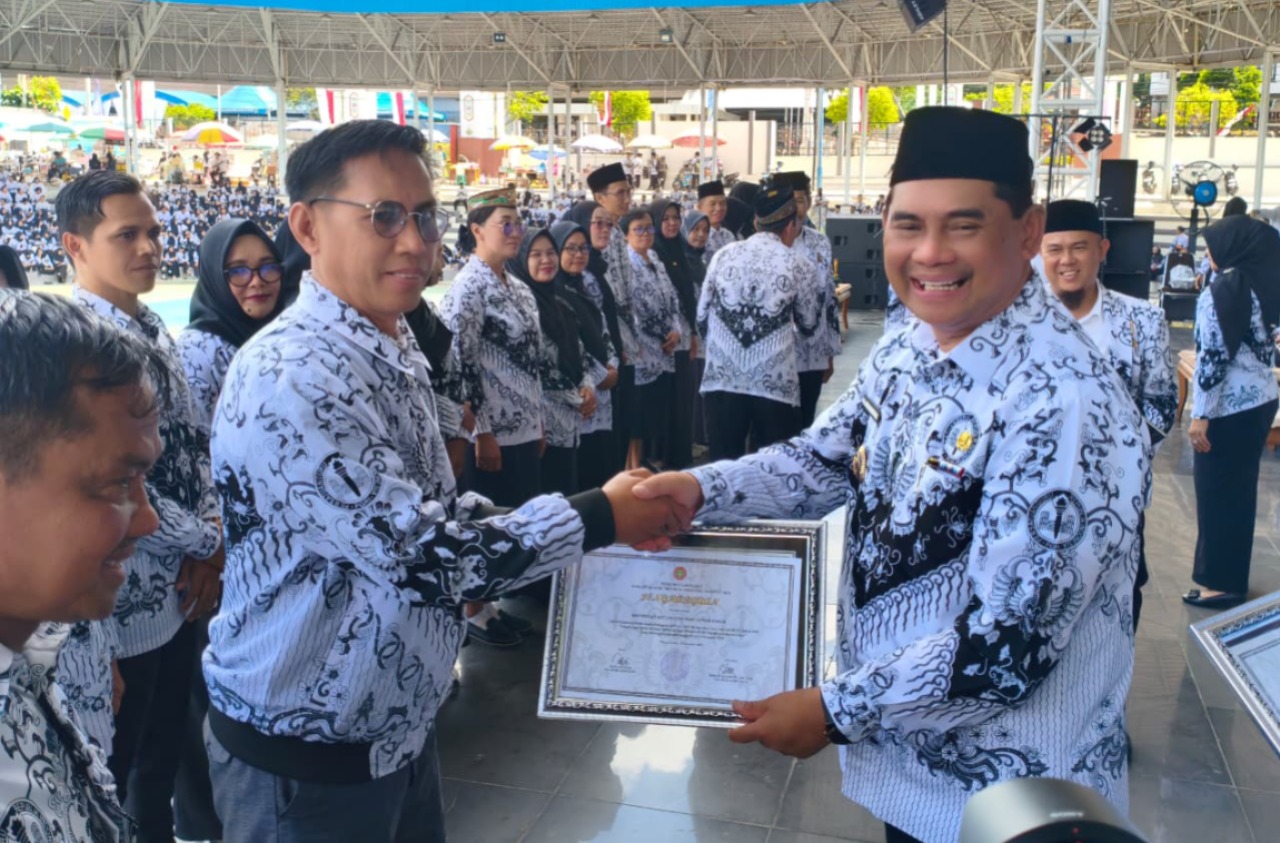 Bupati Shalahuddin (kanan) menyerahkan sertifikat penghargaan kepada guru. RENO SAPUTRA/KALTENG POS