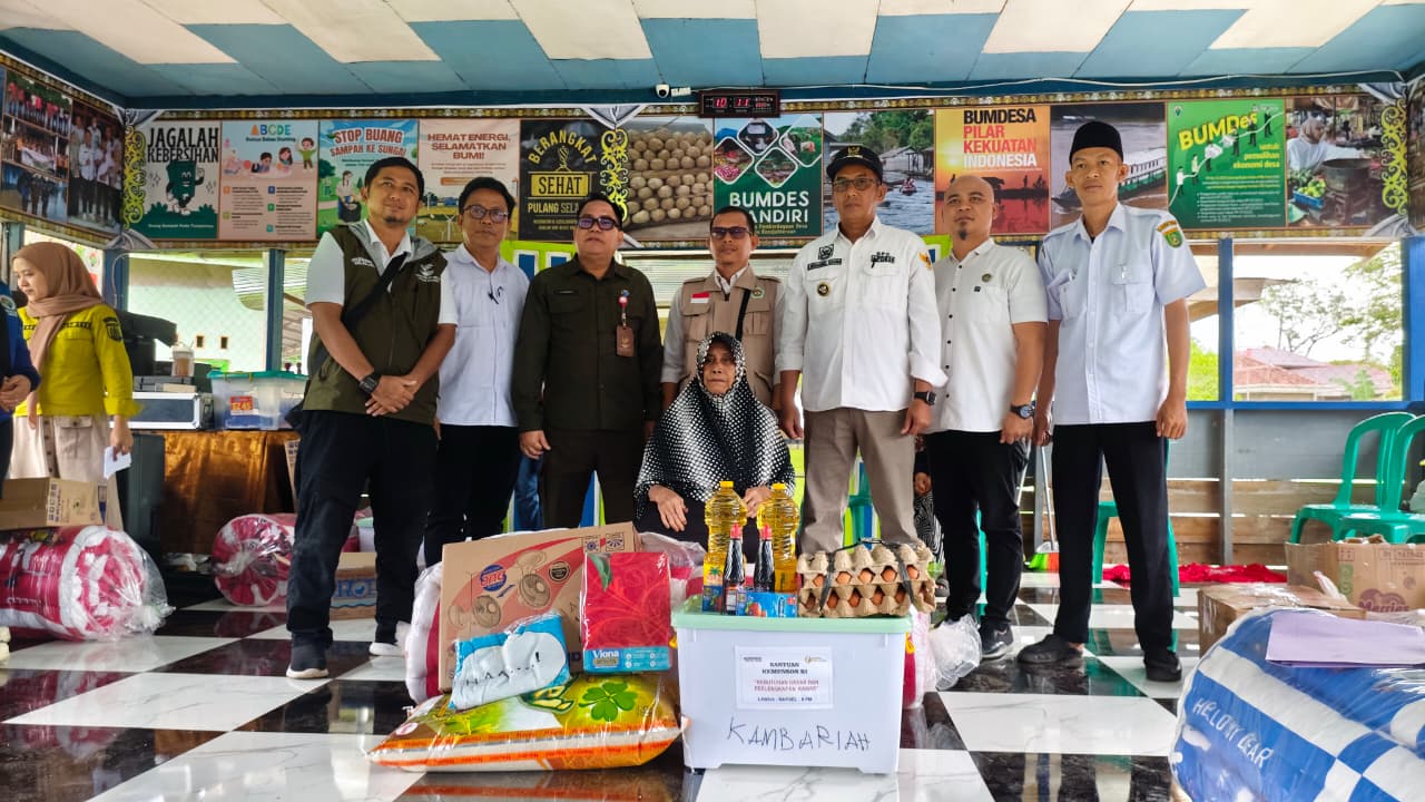 Kadinsos Barsel, Syahdani, didampingi Kades Desa Baru saat menerima bantuan dari Kemensos di Aula Kantor Desa Baru. DENAR/KALTENG POS