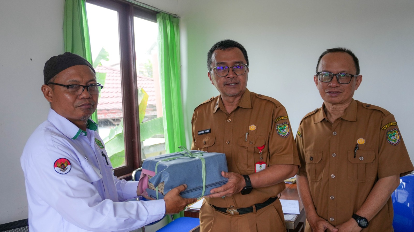 H Afuw (baju putih) menyerahkan Al-Qur&rsquo;an tulisan tangan kepada Dinas Kearsipan dan Perpusatakan Barito Utara. RENO SAPUTRA/KALTENG POS