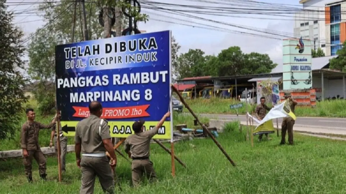 Petugas Satpol PP Kota Palangka Raya menertibkan puluhan reklame liar yang terpasang di bahu jalan, Senin (6/4/2026).