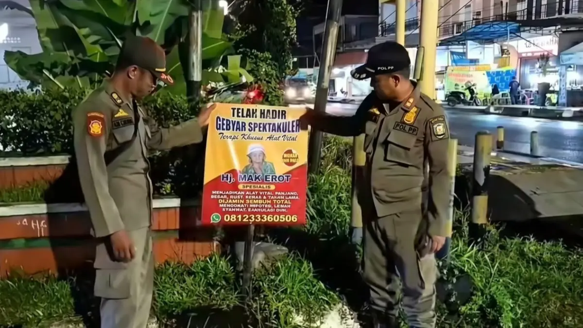 Petugas Satpol PP menurunkan spanduk Mak Erot. Miftah/kaltengpos.jawapos.com