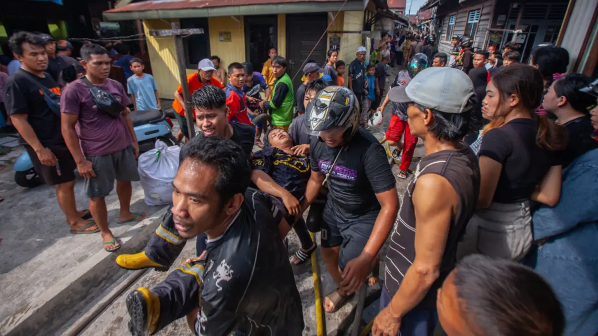 Korban kebakaran Gang Sari Palangka Raya terluka digotong oleh warga.(Arief Prathama/Kalteng Pos)