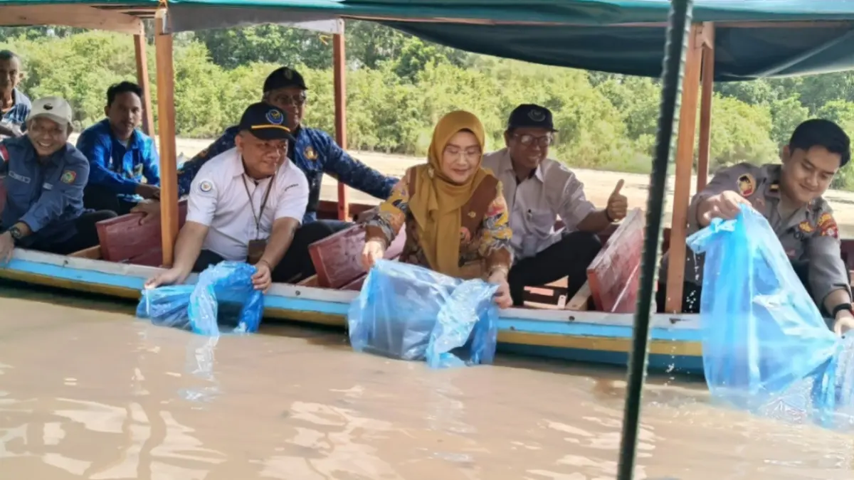 Kadis Perikanan Palangka Raya, Ir Indriarti Ritadewi MAB saat menebarkan benih ikan betok dan gabus di Sei Gohong.(Iyan/Kalteng Pos)