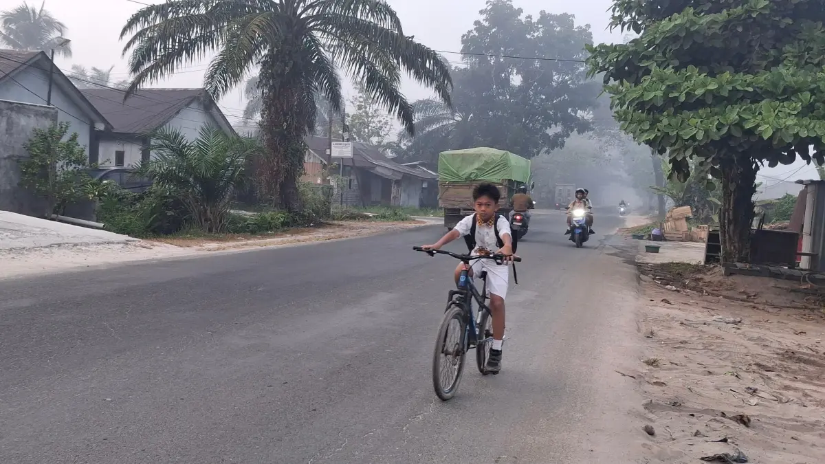 Murid sekolah berangkat di tengah kabut asap yang menyelimuti.(Miftah/kaltengpos.jawapos.com)
