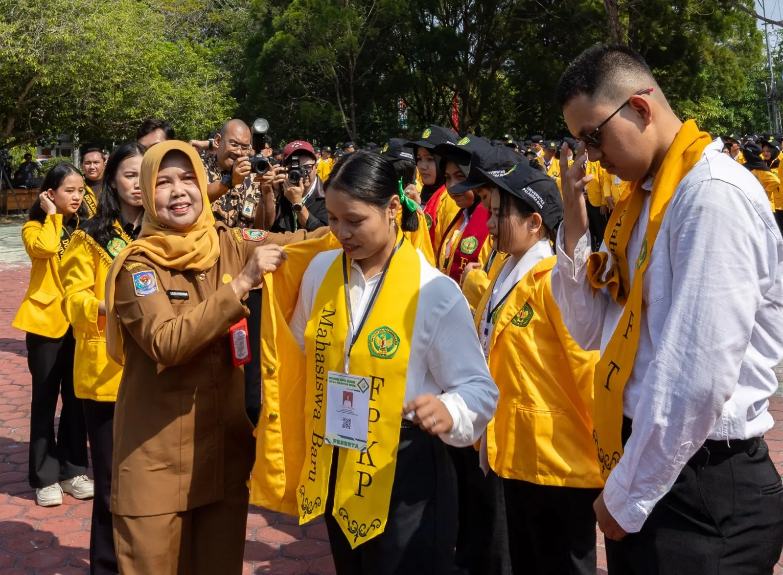 Plt. Asisten I Bidang Pemerintahan dan Kesra, Lisda Arriyana, S.Sos mewakili Gubernur Kalteng, memasangkan tanda peserta kepada mahasiswa baru UPR. 