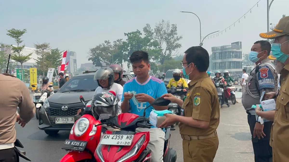 Petugas dari Dinkes Palangka Raya membagikan masker kepada pengguna jalan di tengah kondisi kabut asap yang makin pekat.(Dea/Kalteng Pos)