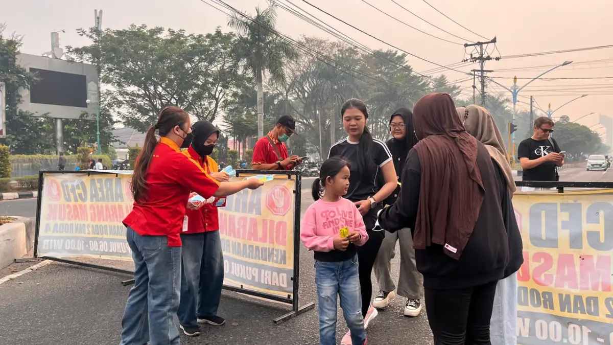 Pegawai Alfamart membagikan masker dan vitamin kepada warga terdampak kabut asap.(Alfamart)