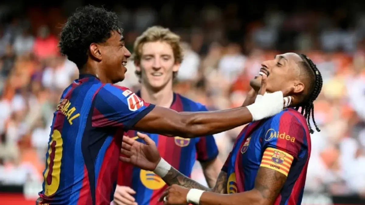 Lamine Yamal berselebrasi dengan rekan setimnya Raphinha dalam laga kontra  Valencia di Estadio Mestalla, Minggu (6/9/2026) malam WIB. Barcelona menang telak 5-0 di laga tersebut. (Sumber: JOSE JORDAN/AFP)