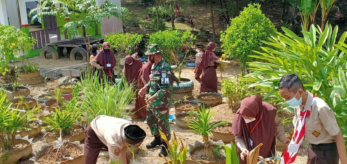 Personel Subdenpom XII/2-3 Muara Teweh bersama Guru SMPN 10 Muara Teweh Kabupaten Barito Utara saat  kerjabakti di lingkungan sekolah.