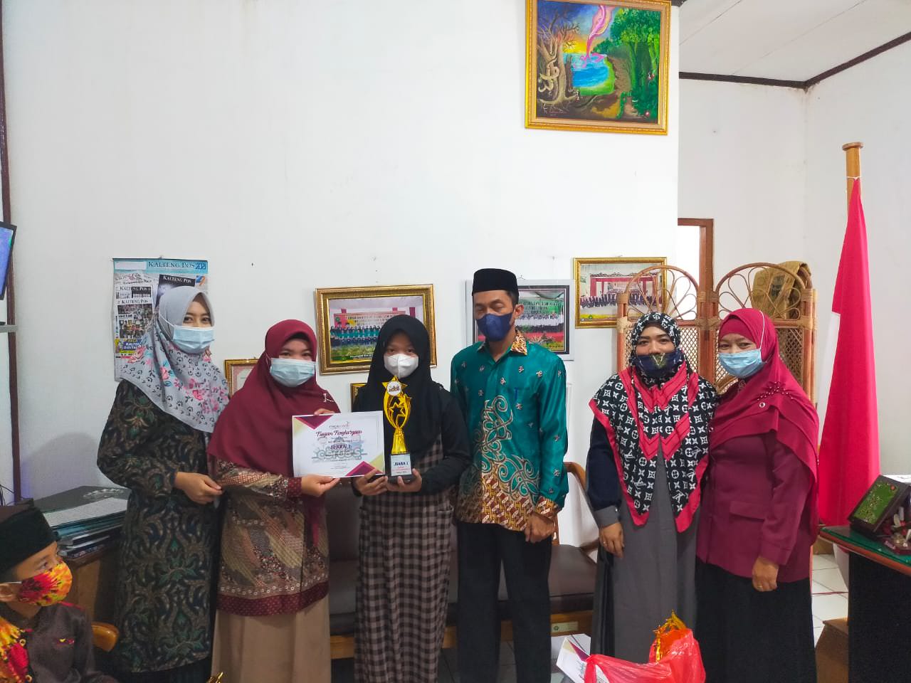 PENYERAHAN PIALA : Dua orang murid didampingi guru menyerahkan tropi kepada Kepala MIN 1 Palangka Raya M Aini. FOTO HUMAS MIN 1