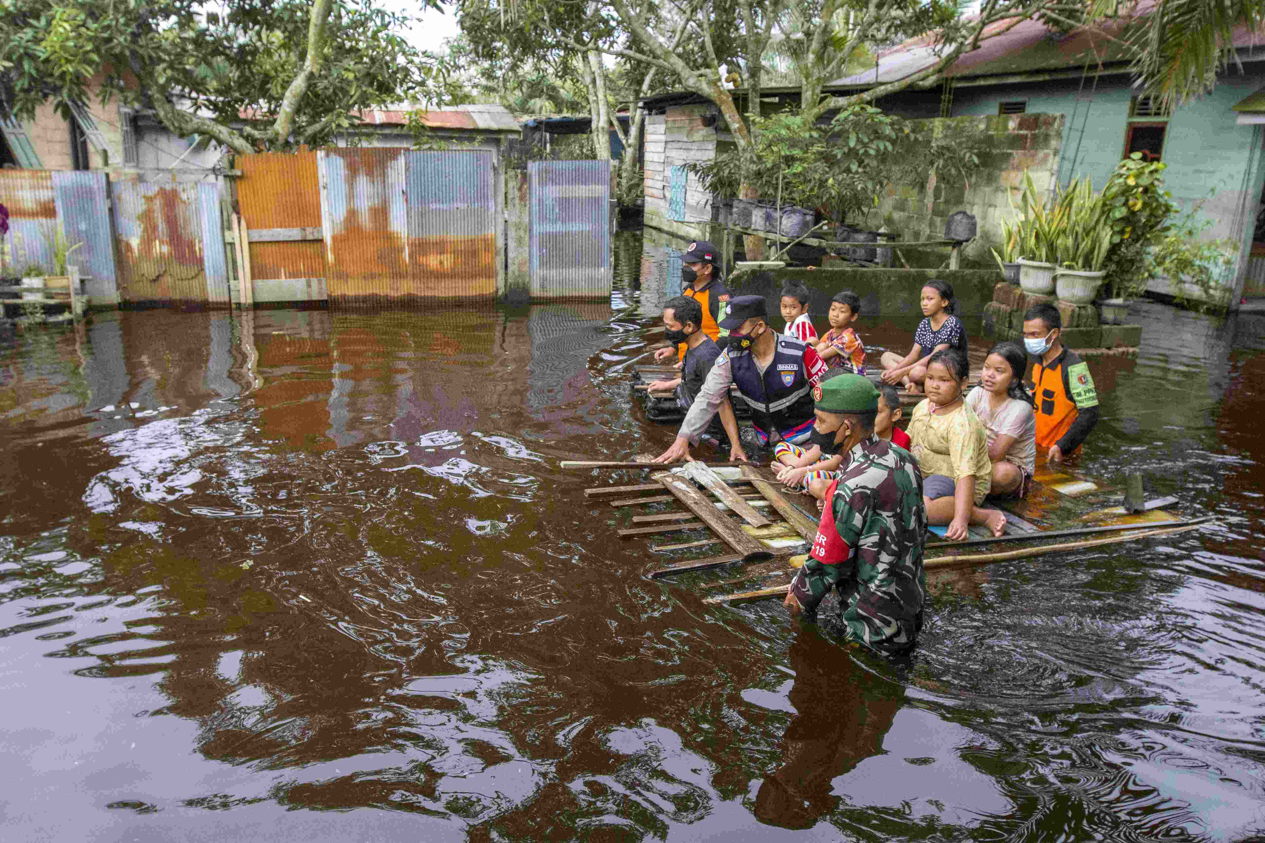 MENJAGA KESELAMATAN WARGA: Petugas yang tergabung dalam Satgas PPKM Kelurahan Kasongan Lama menarik getek berisikan anak-anak untuk membawanya ke tempat aman. Di Gang Saudara RT 11/RW 04, ketinggian air maksimal sampai dada orang dewasa.??