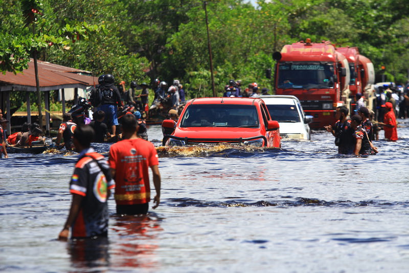 PERJALANAN TERSENDAT: Para pengendara harus antre melintasi jalur trans Kalimantan yang terendam banjir di Desa Tumbang Nusa, Minggu (21/11). DENAR/KALTENG POS