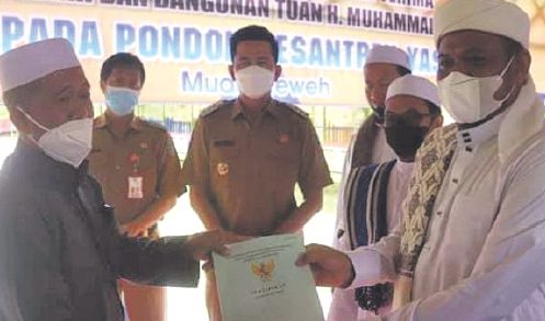 PENYERAHAN SERTIFIKAT: Bupati Barito Utara H Nadalsyah menyaksikan penyerahan sertifi kat wakaf tanah dan bangunan milik HM Fuadi kepada Pimpinan Pondok Pesantren Yasin Muara Teweh KH Rusmadi Darsani LC di Dusun Pangku Raya, Kelurahan Melayu, Kecamatan Te