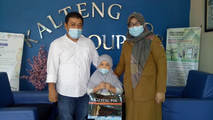 APRESIASI: Afifa didampingi kedua orangtuanya Agustian Dewantara dan  Ria mendapatkan bingkisan dari Kalteng Pos setelah hasil mewarnai gambar di koran terpilih sebagai pemenang. (FOTO: HENY/KALTENG POS)