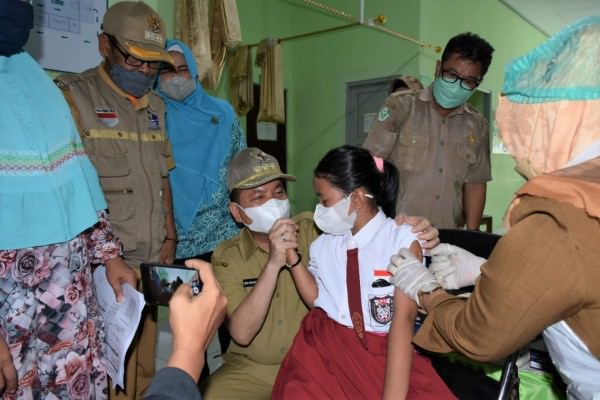 DAMPINGI: Bupati Kapuas Ben Brahim S Bahat mendampingi salah satu anak yang sedang menerima vaksinasi Covid-19, belum lama ini.