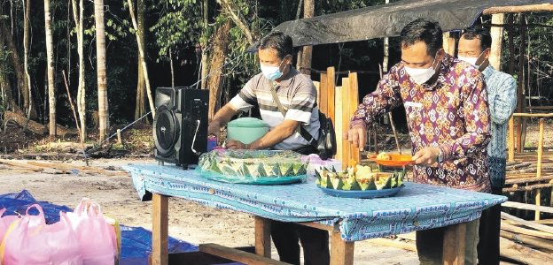 SYUKURAN: Camat Bukit Batu Hendrikus Satria Budi (baju batik) saat memotong tumpeng pada acara syukuran pembukaan objek wisata baru di Kelurahan Sei Gohong, baru-baru ini. (KECAMATAN BUKIT BATU UNTUK KALTENG POS)