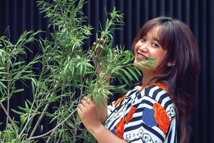 Gabrielle Krissta merawat Melaleuca Leucadendra di halaman rumahnya. Tanaman ini bisa ditaruh di ruang tamu atau kamar untuk pengusir nyamuk. (ALLEX QOMARULLAH/JAWA POS)