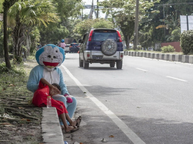 FENOMENA BADUT JALANAN: Seorang badut jalanan dengan karakter kartun doraemon saat duduk di Jalan A Yani, Palangka Raya. FOTO: AGUS PRAMONO/KALTENG POS