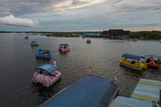 RAMAI: Para wisatawan antusias berkunjung ke Wisata Air Hitam di kawasan Dermaga Kereng Bangkirai, Kota Palangka Raya dan mencoba berbagai wahana seperti sepeda air bebek, Minggu (30/4).