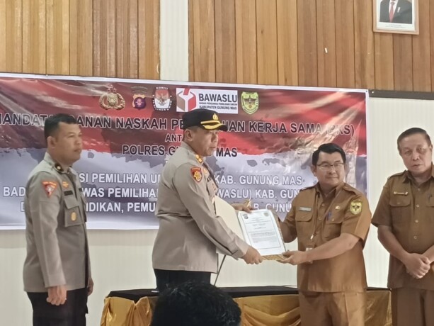 FOTO HUMAS UNTUK KALTENG POS KERJA SAMA : Kapolres Gunung Mas AKBP Asep Bangbang Saputra dan Plt Kepala Disdikpora Gumas Aprianto menunjukkan MoU polisi masuk sekolah yang sudah ditandatangani di Aula Bhayangkari Mapolres setempat, Senin (22/5).