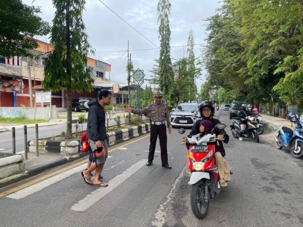PENGATURAN: Personel Satlantas Polres Kotim gatur pagi sambil bantu pejalan kaki menyeberang jalan.