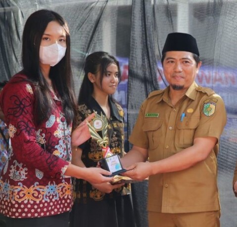 PIALA: Plt Kepala Dinas Perpustakaan dan Kearsipan Kota Palangka Raya, Fauzi Rahman menyerahkan piala kepada salah satu duta bahasa, Senin (26/6).