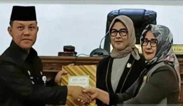 MENYERAHKAN : Wakil Ketua I DPRD Barito Selatan Hj Nyimas Artika saat menyerahkan raperda kepada Pj Bupati Barsel Deddy Winarwan pada rapat paripurna di DPRD Barsel, Selasa (25/7).