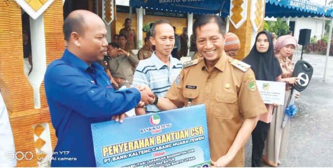 SIMBOLIS : Deni Alamsyah mewakili Pemimpin Bank Kalteng Cabang Muara Teweh Citra Deni menyerahkan bantuan CSR untuk rehabilitasi lapangan Badminton GOR Panglima Batur yang diterima oleh Pj Bupati Barito Utara Drs Muhlis (kanan) saat pelaksanaan upacara Ha