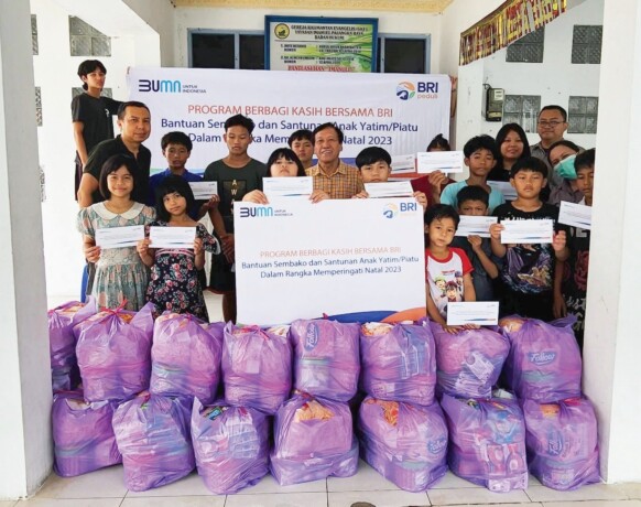 KEBERSAMAAN : SPO BRI Cabang Palangka Raya, Robby Teguh Saputra (paling kiri tengah) dan Sekretaris Yayasan Imanuel Palangka Raya, Holdrich Nahason (tengah baju kuning), saat berfoto bersama anak anak panti, Kamis (28/12).