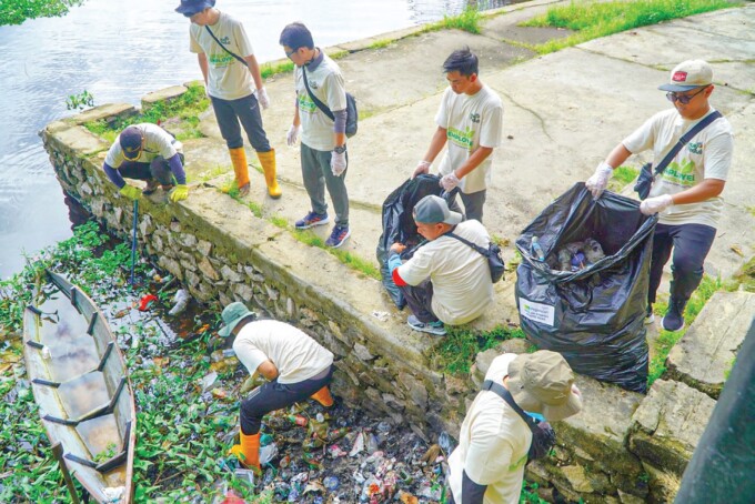 RELAWAN : Pegawai PLN membersihkan sampah di sekitar Jembatan Kahayan, Palangka Raya, kemarin.