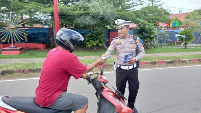 SOSIALISASI : Personel Satlantas Mura membagikan leaflet kepada pengendara