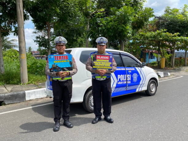 IMBAUAN: Personel Satlantas Polres Kapuas memegang plang imbauan di sela patroli siang di sekitar Kota Kuala Kapuas, Senin (5/8/2024).