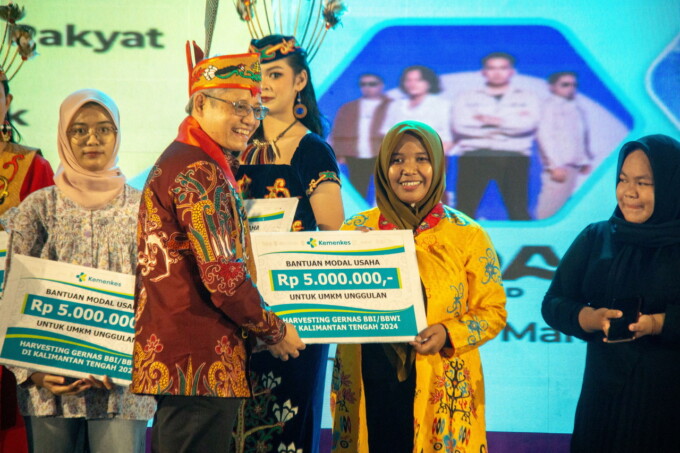 MODAL USAHA: Sekjen Kemenkes RI Kunta Wibawa Dasa Nugraha menyerahkan bantuan modal usaha kepada Siti Mustikatun yang merupakan pelaku UMKM unggulan di GPU Tambun Bungai, Kamis (14/8/2024).
