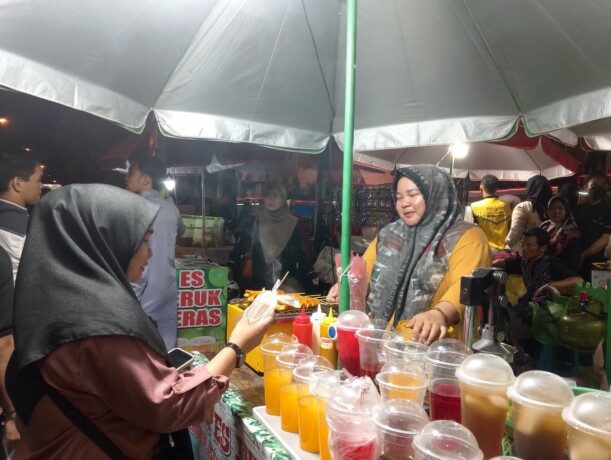 BERKAH MTQ: Mama Ayu saat melayani pembeli di stan dagangannya pada pembukaan MTQ Korpri Nasional di halaman Kantor Gubernur Kalteng, Senin malam (4/11/2024).