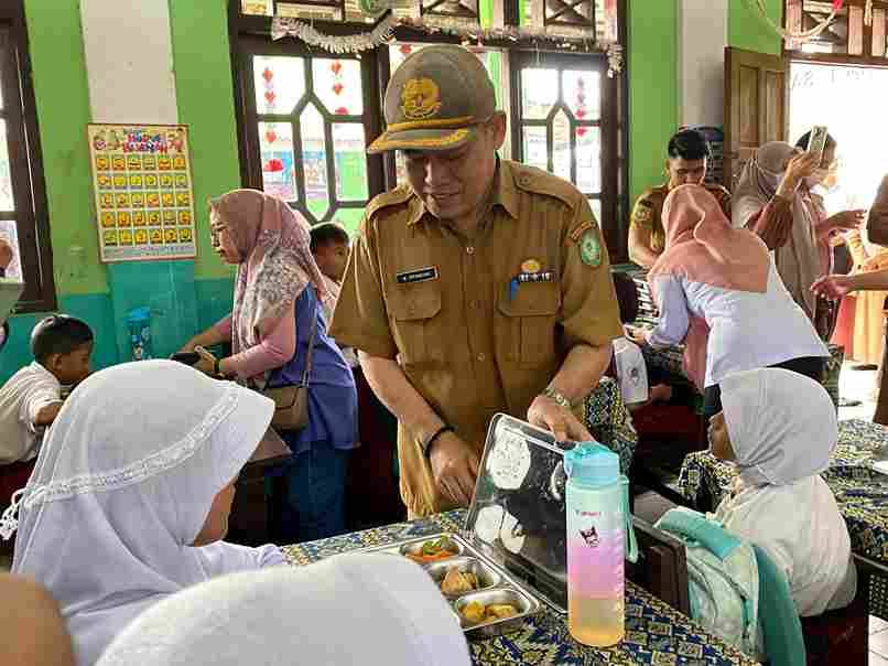 BAGI MAKANAN : Kepala Dinas Pendidikan Kotawaringin Timur Muhammad Irfansyah saat membagikan makanan bergizi gratis kepada para murid, beberapa waktu lalu. MIFTAH/KALTENG POS