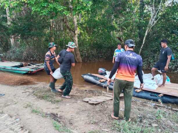 ANGKUT MATERIAL : Satgas TMMD bersama masyarakat baju membahu membawa material melalui jalur sungai.