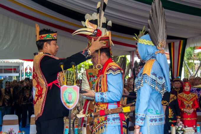 GELAR KEHORMATAN: Gubernur Kalteng, H Agustiar Sabran dan dan istri Aisyah Thisia Agustiar Sabran menerima gelar kehormatan adat Dayak di hari jadi Provinsi Kalteng ke 68 di halaman Kantor Gubernur, Jumat (23/5). (Arief Prathama/ Kalteng Pos)