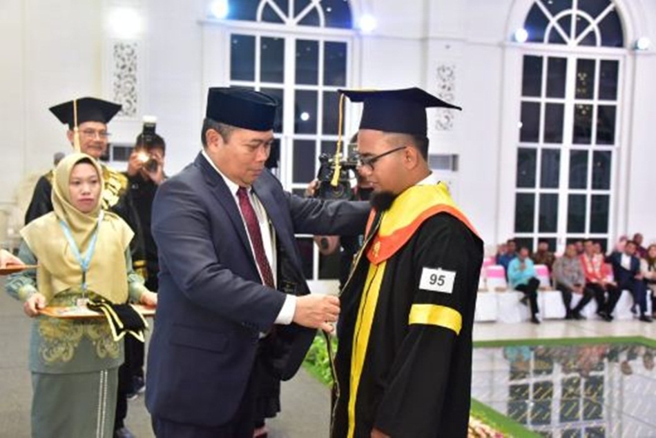 Penjagub Gorontalo Ismail Pakaya saat menyrmatkan selempang kepada wisudawan   terbaik Universitas Terbuka Gorontalo tahun 2023, di gedung Graha Azizah. (Foto &ndash; Andika)
